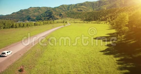 在山丘和草地上蜿蜒的道路上飞过汽车下面是农村公路视频的预览图