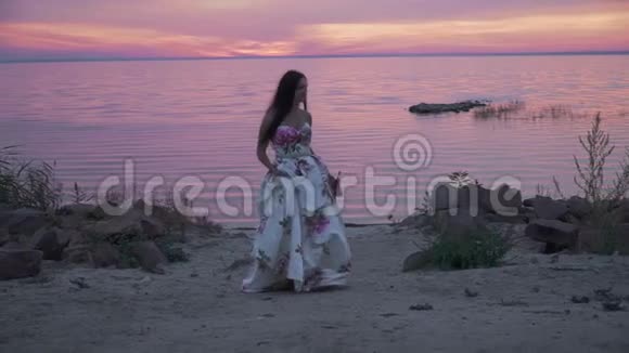 在美丽的海滩上穿着长裙的迷人女士视频的预览图