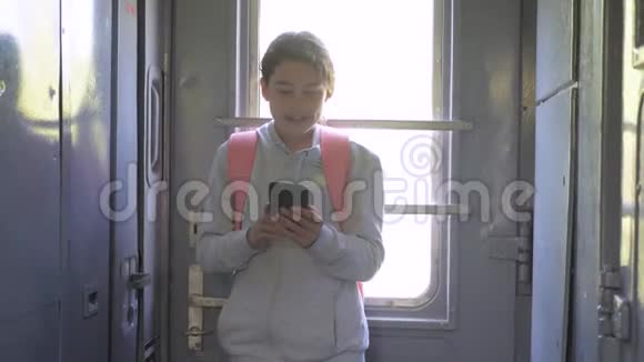 带背包的少女旅行者站在火车的窗户边手里拿着一部智能手机生活方式旅行视频的预览图