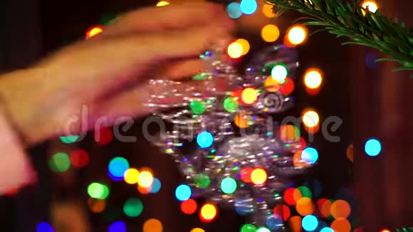 手女人用圣诞彩灯装饰圣诞树视频的预览图
