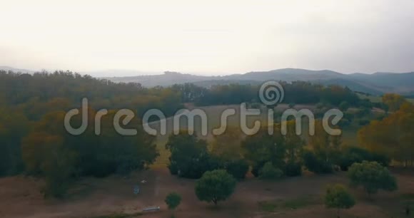 高空飞行低空飞行日落时飞越丘陵和马球场视频的预览图