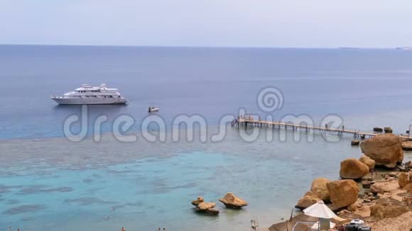 岩石海滩有雨伞靠近珊瑚礁的红海悬崖埃及视频的预览图