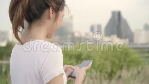 性格开朗的亚洲旅游博客女性在街上行走时在智能手机上使用触摸屏技术视频的预览图
