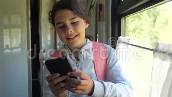 带背包的少女旅行者站在装有智能手机的火车车窗旁生活方式旅行视频的预览图