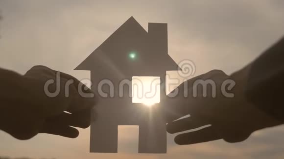幸福家园建设理念在日落的剪影阳光下一个人手里拿着一个纸房子生活视频的预览图