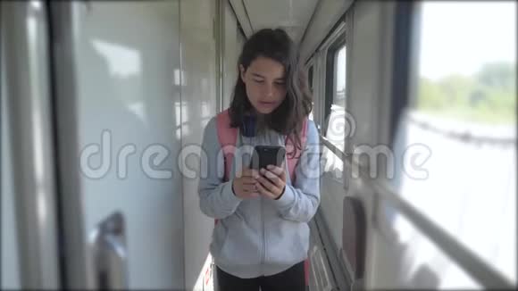 十几岁的女孩走在火车车厢里带着背包的生活方式和智能手机交通运输视频的预览图