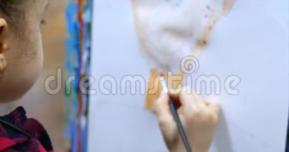 年轻可爱的女艺术家在一个艺术工作室坐在一个Easel和绘画画布绘图过程视频的预览图