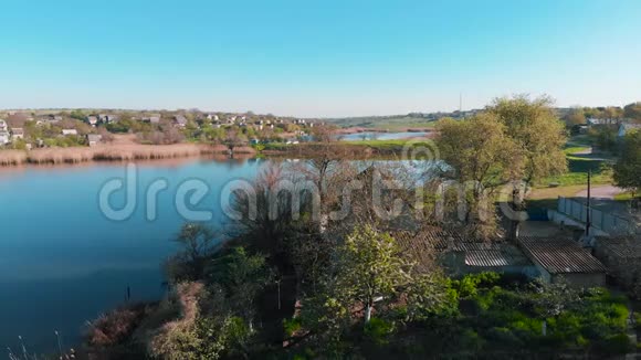上午在池塘岸边山上鸟瞰乡村房屋视频的预览图