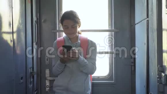 年轻的女旅行者带着背包站在生活方式的窗口火车上有一部智能手机旅费视频的预览图