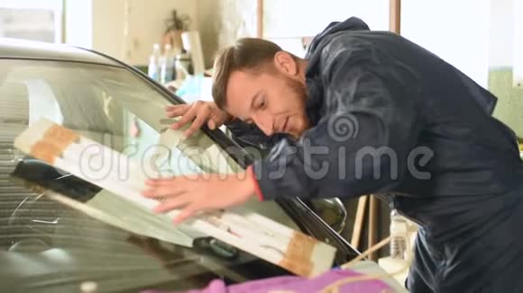 在车间从事消除汽车挡风玻璃裂缝的专业人员的特写视频的预览图
