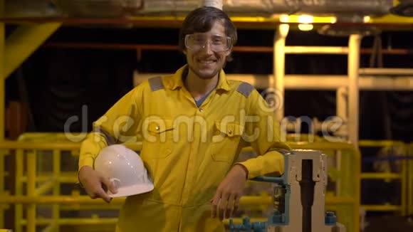 在工业环境石油平台或液化气体工厂穿黄色工作服戴眼镜和戴头盔的年轻人视频的预览图