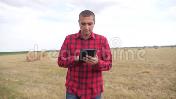 智慧生活方式农耕农业理念一个农夫在数字平板电脑上的田野里研究干草堆慢动作视频的预览图