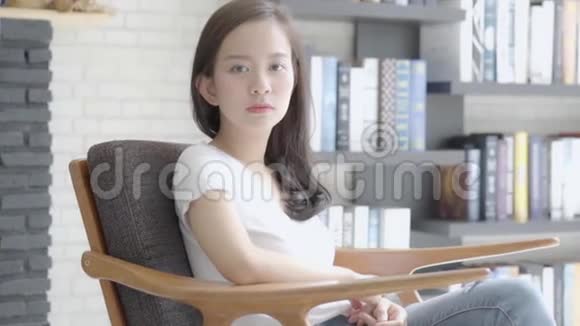 美丽的肖像年轻的亚洲女人坐在沙发上微笑着在客厅里快乐着视频的预览图