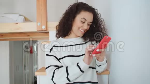 年轻的女人在家里用手机视频的预览图