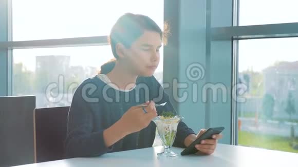 机场等待乘飞机的生活方式十几岁的女孩吃沙拉看上去像智能手机在咖啡馆里上网机场视频的预览图