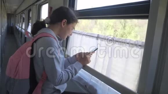 带背包的少女旅行者站在火车的窗户边生活方式与智能手机旅费视频的预览图