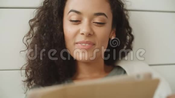 漂亮的年轻女人在家里使用数字平板电脑视频的预览图