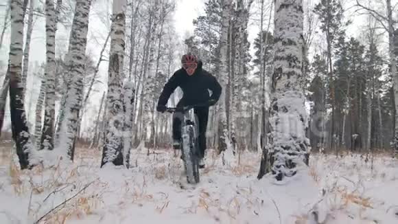 专业的极限运动员骑着一辆肥胖的自行车在户外骑自行车在冬天的雪林里人类视频的预览图