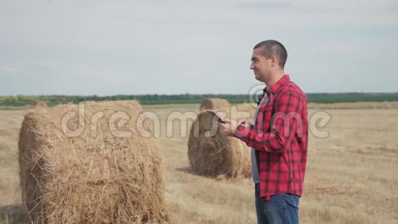 智慧农业理念男子农民工人的生活方式研究干草堆在一个领域的数字平板电脑慢慢慢慢视频的预览图