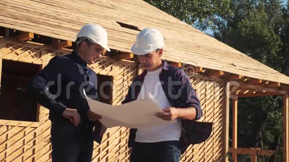 团队合作概念建设构建建筑师慢动作视频两名戴头盔的建筑工人研究房屋计划视频的预览图