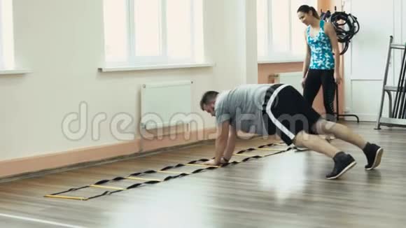 厚肥胖的家伙和个人苗条教练一起做体育锻炼超重男女训练员视频的预览图