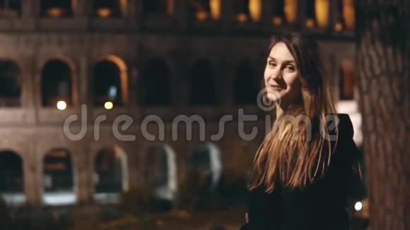 慢点年轻漂亮的女人回头看镜头用手指在意大利罗马的竞技场上展示视频的预览图