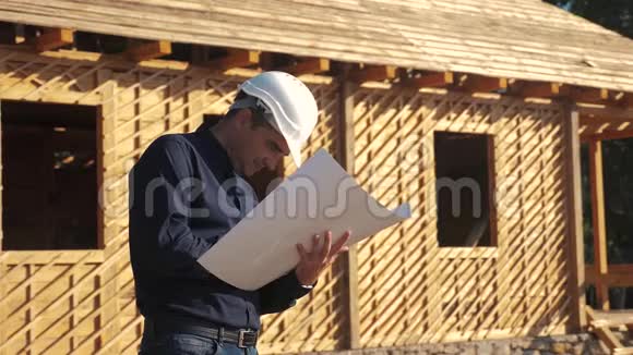 概念建筑构建建筑师慢动作视频戴着头盔的建筑工人站在一座建筑上手持一个视频的预览图