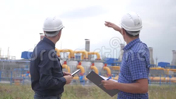 团队合作工业煤气生产站的概念慢动作视频两位戴着头盔的生活方式工程师正在学习视频的预览图