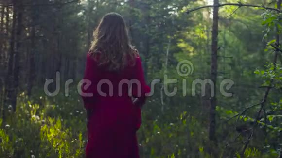 穿着红衣服在森林里散步的年轻女子视频的预览图