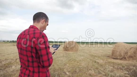 智慧农业理念一个农夫在一个生活方式的数码平板电脑上研究干草堆慢动作视频的预览图