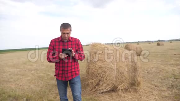 智慧农业理念男人农民的生活方式研究干草堆在一个领域的数字平板电脑慢动作视频的预览图
