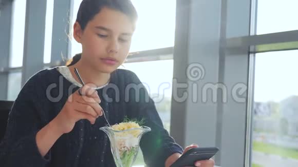 机场等待乘坐飞机的生活方式十几岁的女孩吃沙拉看上去像智能手机在咖啡馆里上网机场视频的预览图