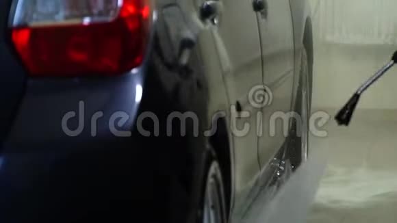 洗车洗车机清洗汽车一个洗车工人用水洗一辆车特写镜头视频的预览图