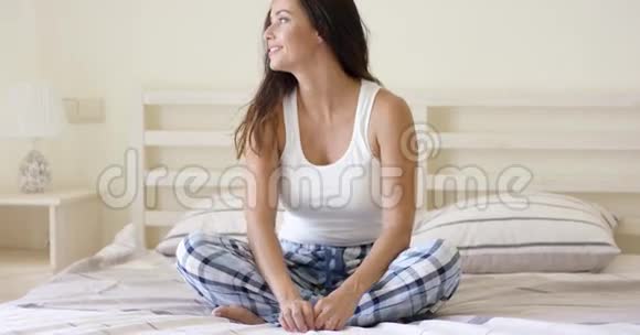 穿格子睡衣的女人坐在床上视频的预览图