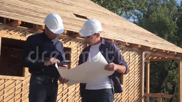 团队合作概念建设构建建筑师慢动作视频两个戴头盔的建筑工人研究房屋计划视频的预览图