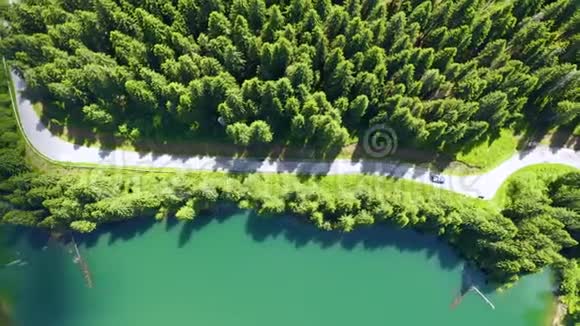 从飞机上可以看到汽车行驶在前方和湖边美丽的山路在山路上开车道路视频的预览图