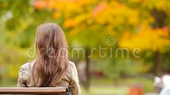 美丽的女人享受秋天公园秋天落叶下温暖的一天视频的预览图