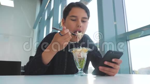 机场等待飞机航班十几岁的女孩吃沙拉看上去像智能手机咖啡馆里的网络生活方式机场视频的预览图
