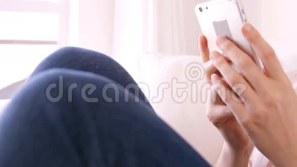 金发女人用智能手机坐在沙发上视频的预览图