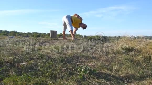 在户外练习瑜伽动作和姿势的人年轻男子站在瑜伽姿势的自然做体力活的运动员视频的预览图