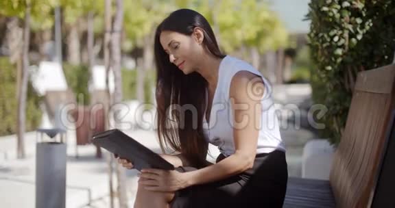 女商人在城市公园里用平板电脑视频的预览图