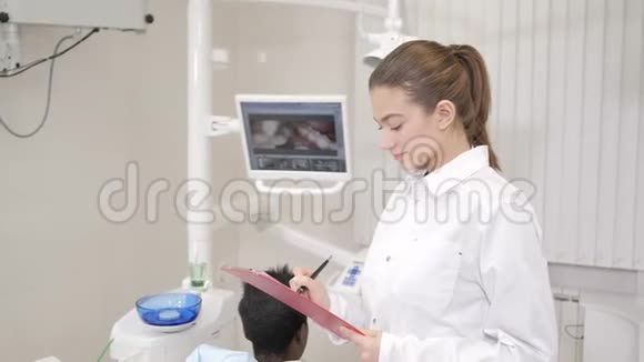 漂亮的女医生牙医年轻的非裔美国男性病人在牙科诊所的椅子上医学卫生视频的预览图