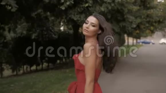 穿红色连衣裙的时尚女性肖像散步女孩视频的预览图