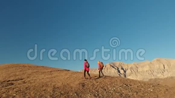 两个女孩的旅行者带着背包和照相机漫步在山上史诗般的岩石之间视频的预览图