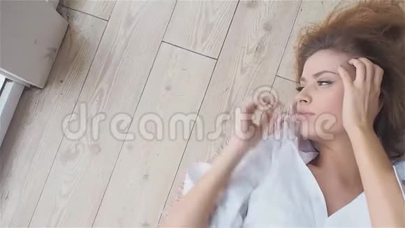 穿着白色衬衫的漂亮年轻女人躺在地板上视频的预览图