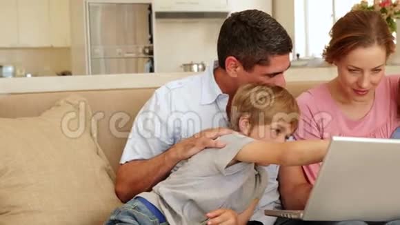 幸福的一家人一起坐在沙发上用笔记本电脑视频的预览图