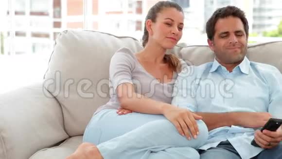 放松的夫妇在沙发上看电视视频的预览图