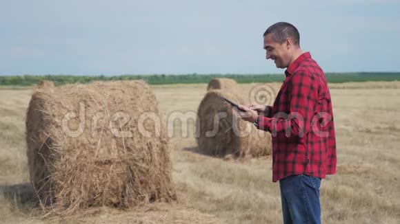 智慧农业理念一个工人农民在数字平板电脑上的田野里研究干草堆生活方式缓慢视频的预览图