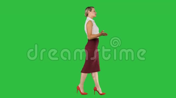 美丽的女人在绿色屏幕上说话和走路彩色键视频的预览图