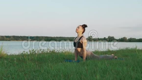 美丽的年轻女子早上在蓝色瑜伽垫上做瑜伽安静的风景视频的预览图